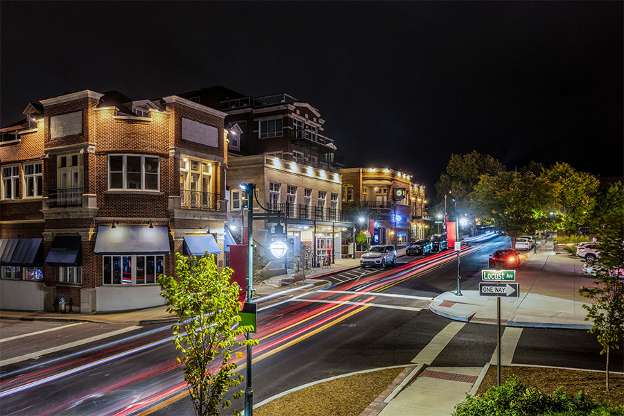 A shot of Locust St in downtown Fayetteville, AR at night as cars drive up and down the street