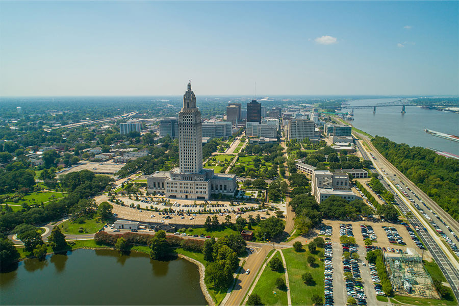 A daytime aerial view of the State Capitol of Louisiana with downtown Baton Rouge in the background and the Mississippi River