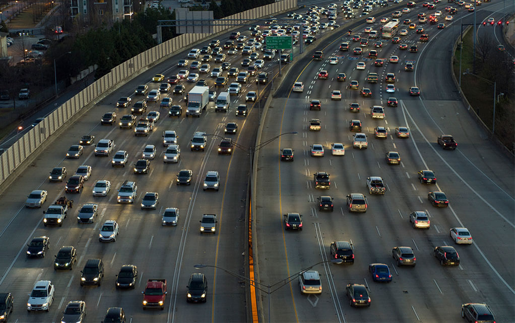 Aerial view of a congested American interstate as cars line all the lanes of travel in both directions at dusk