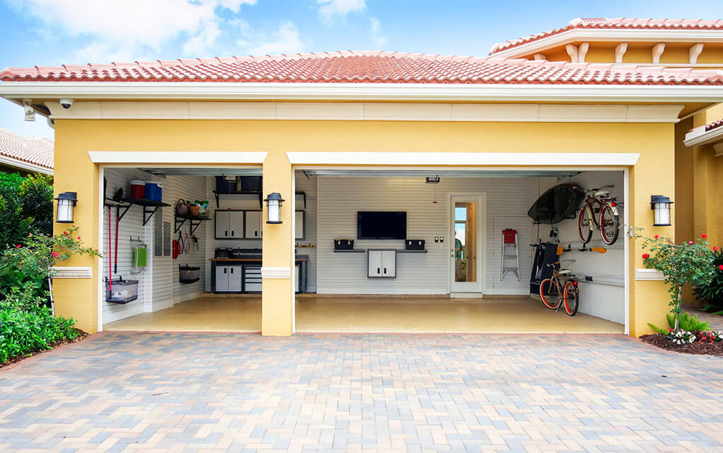 View of an open garage with stuff inside and no cars inside of an upscale home