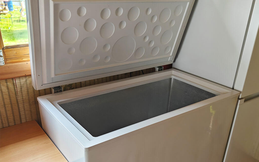 View of an open freezer chest inside of a home with nothing inside of it.