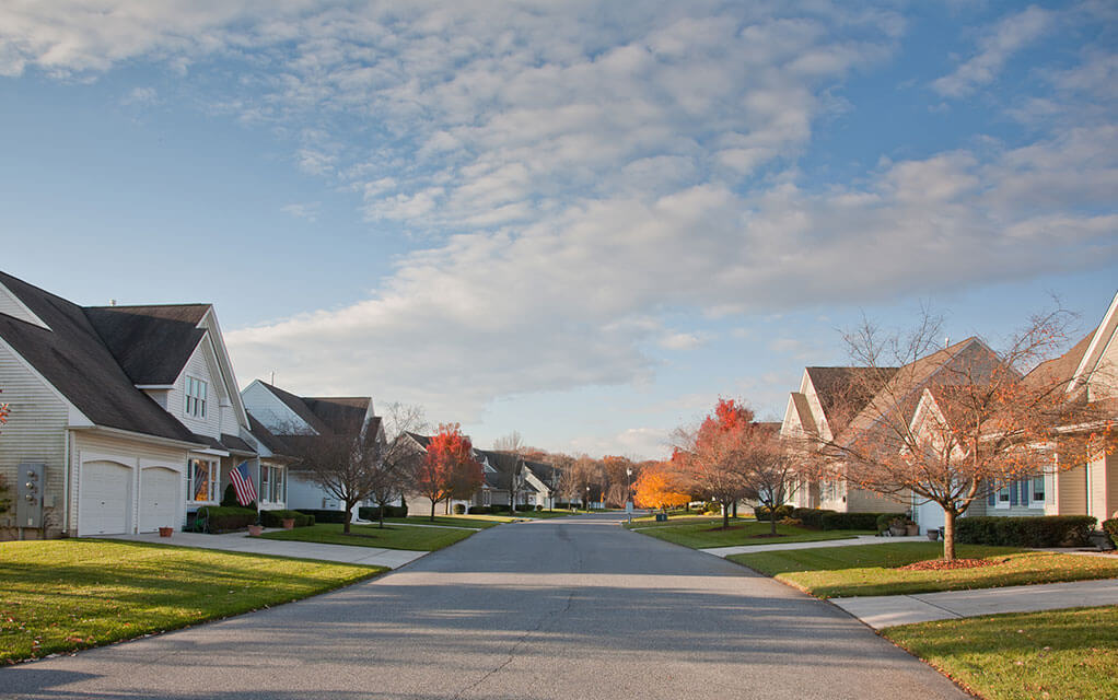 The view down a quiet and pretty neighborhood street one early fall evening on a mostly sunny day