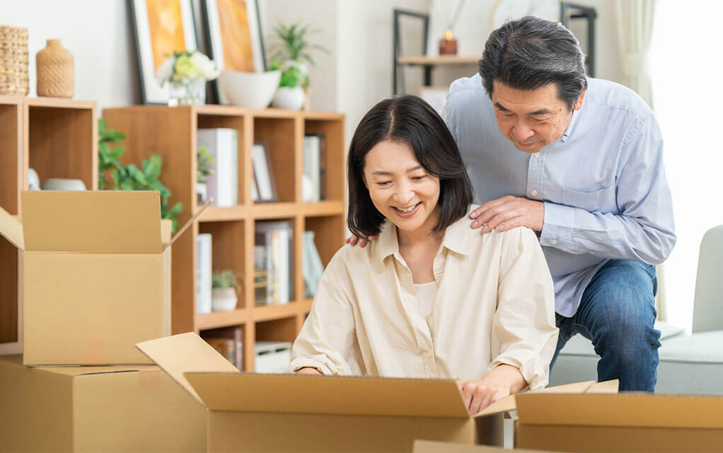 An older couple looks through their moving boxes as they unpack in their home
