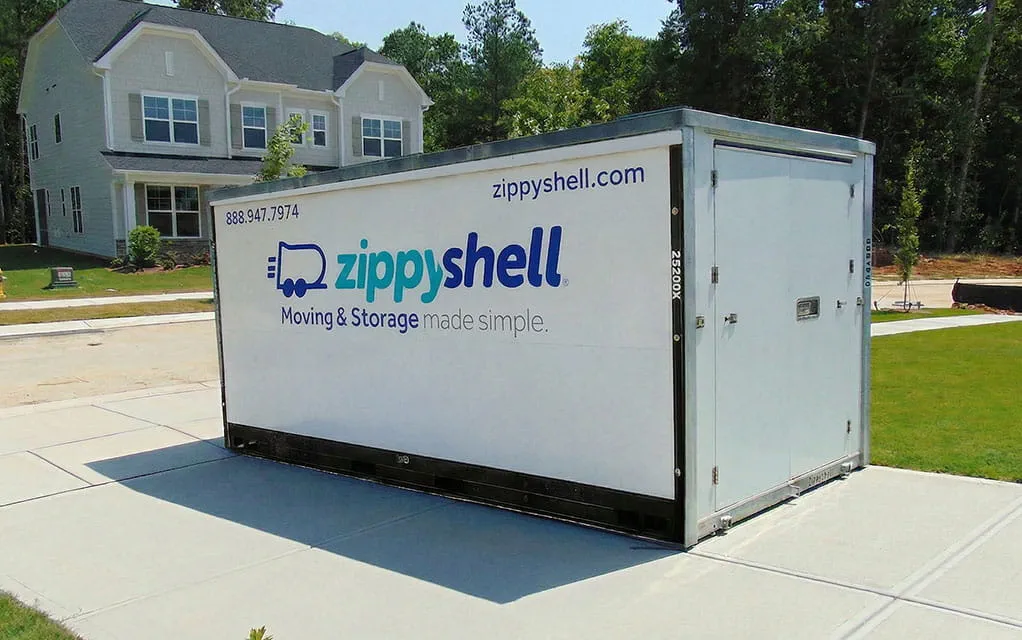 A Zippy Shell portable storage container sits in a home's driveway waiting to be packed