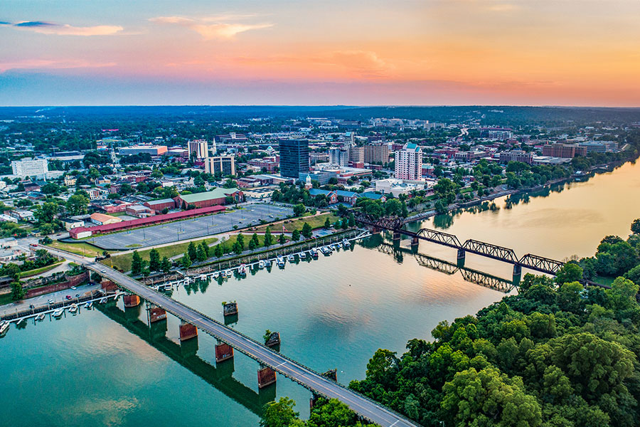 A view of the Savannah River and bridges that span it from the downtown August, GA area that is in the background as the sunsets on a clear, spring day