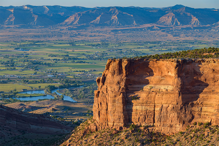 A beautiful view of part of the Colorado National Monument located near Grand Junction, CO on a beautiful sunny day with a smattering of homes and acreage in the background
