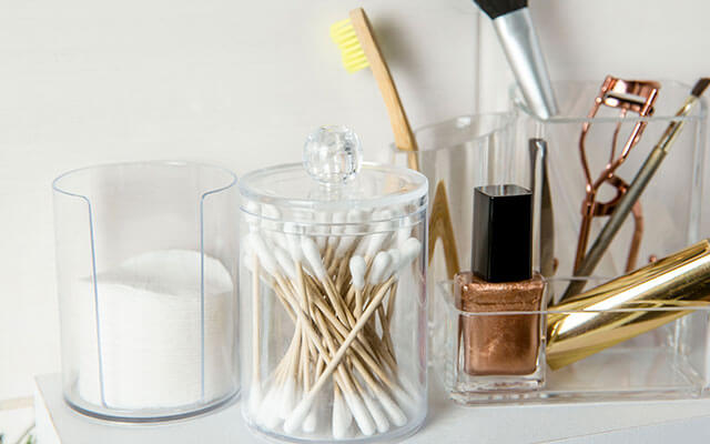 Epsom salts, q tips, and other miscellaneous items sit in small plastic containers on a bathroom counter